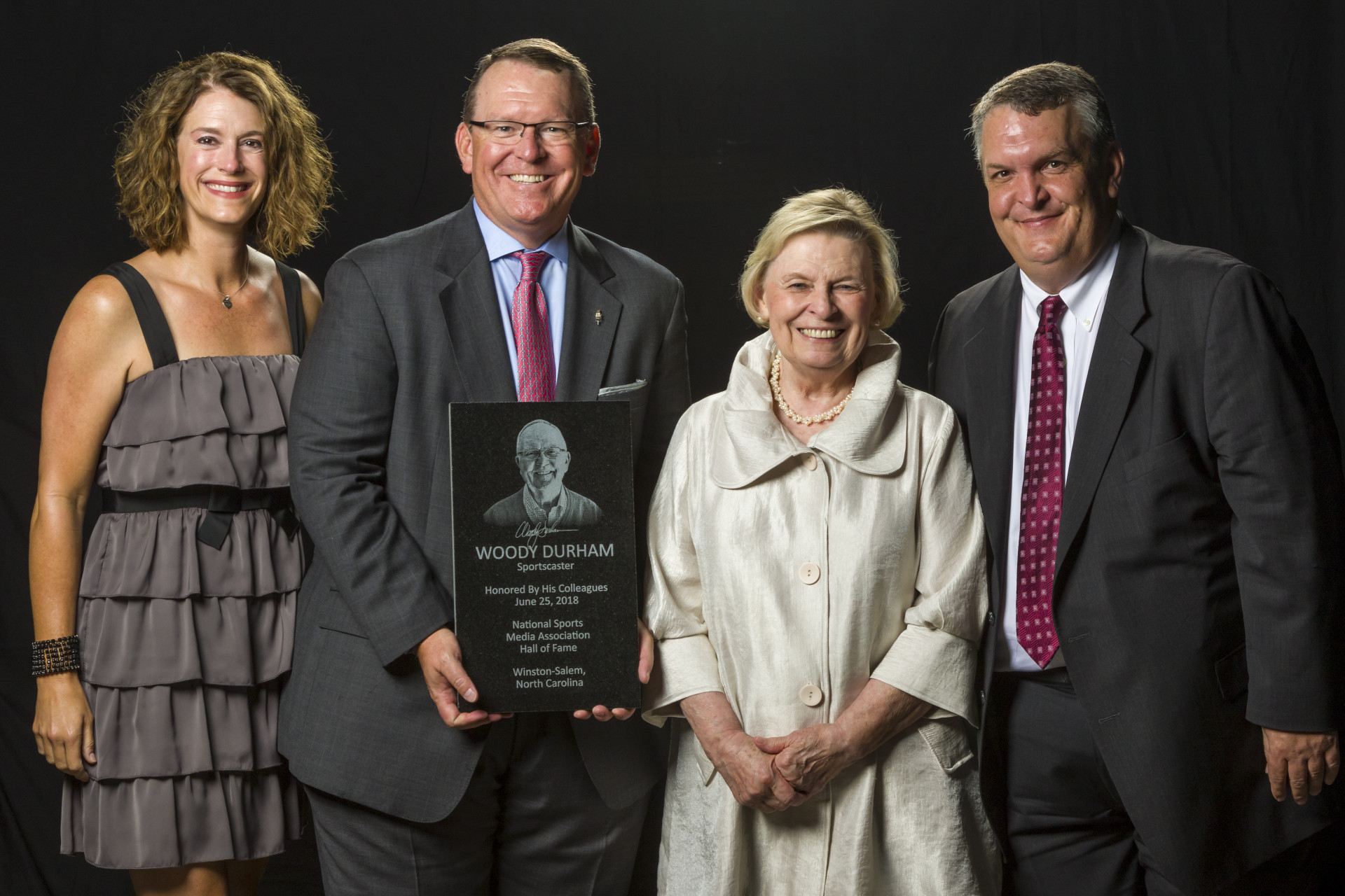 Woody Durham's family -- from left, Victoria Durham (daughter-in-law), Wes Durham (son), Jean Durham (widow), Taylor Durham (son) -- with his Hall of Fame plaque (Photo by Bob Leverone)