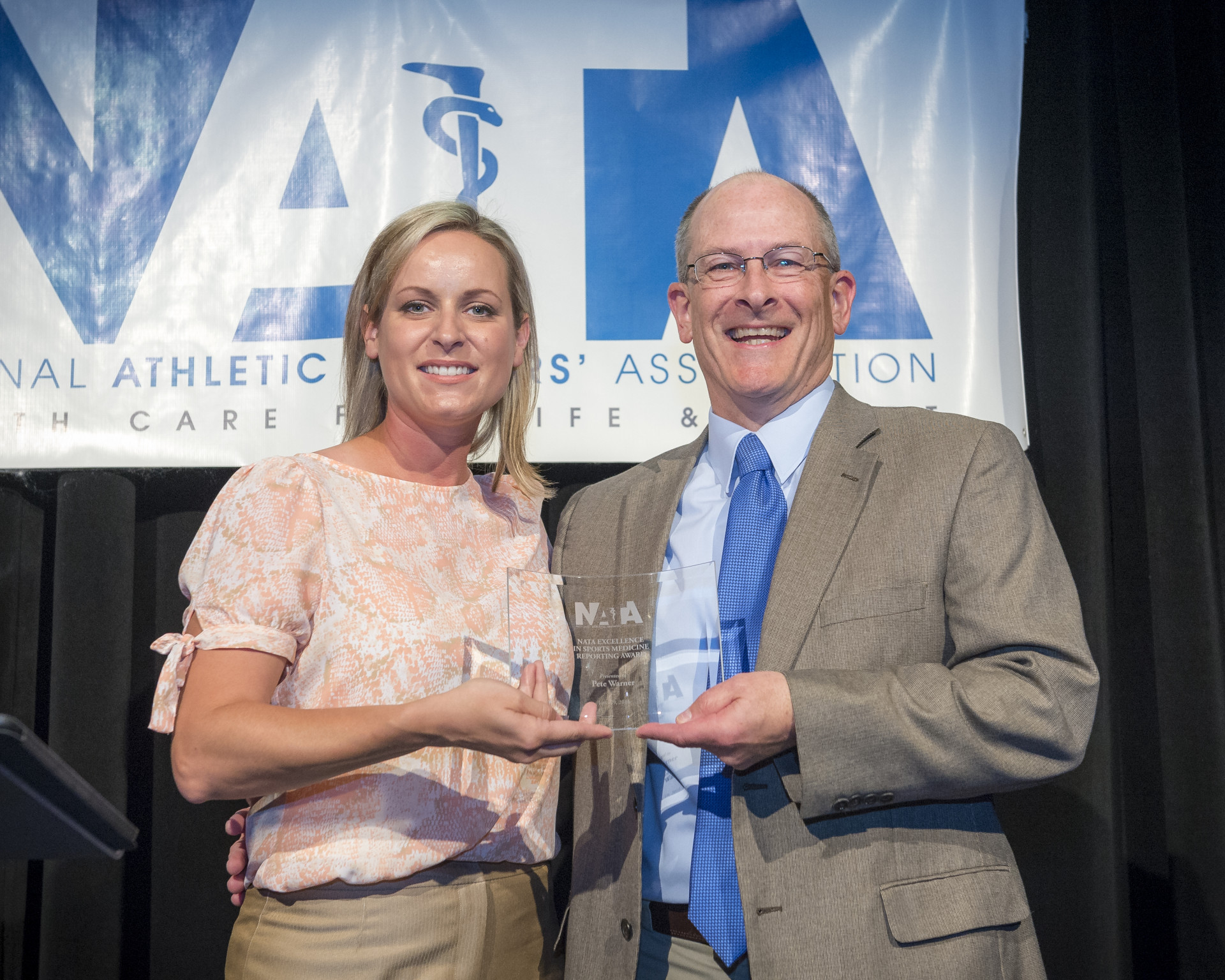 Pete Warner (right) accepts the 2016 NATA Sports Medicine Reporting Award from NATA’s Jamie Woodall (Sean Meyers Photography)