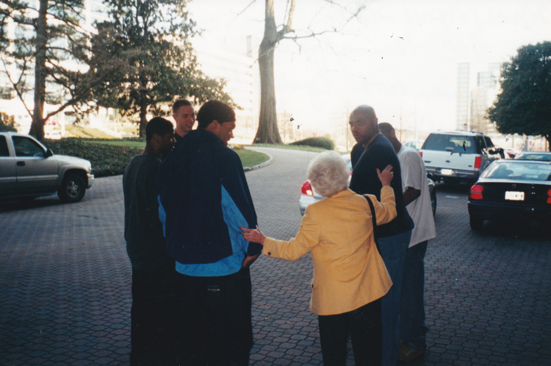 Ann Spencer (yellow jacket, back to camera) talks to a group of University of North Carolina basketball players, along with tv analyst Charles Barkley (second from right)