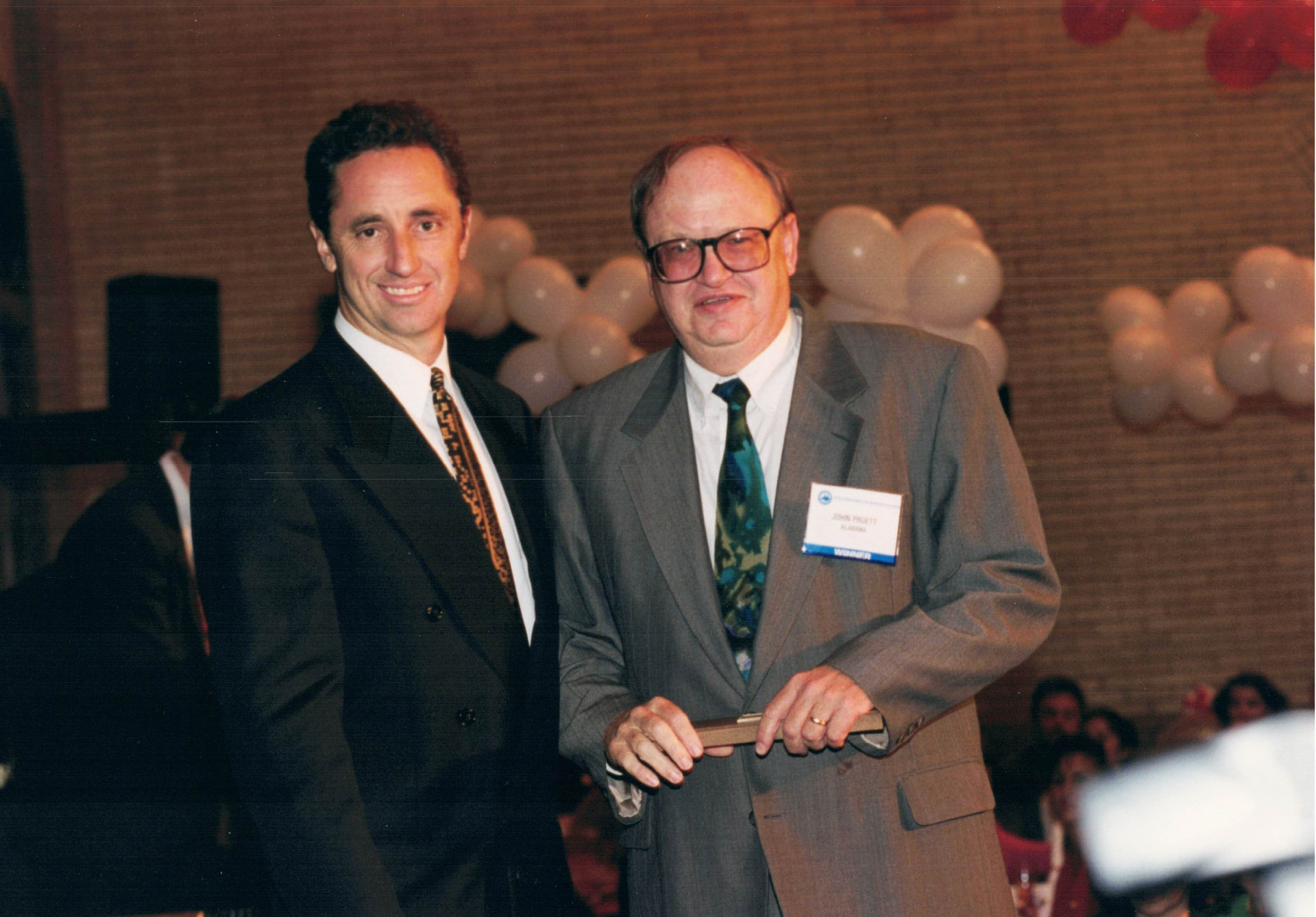 John Pruett (right), receives his 1995 NSSA Alabama Sportswriter of the Year Award from Rick Reilly